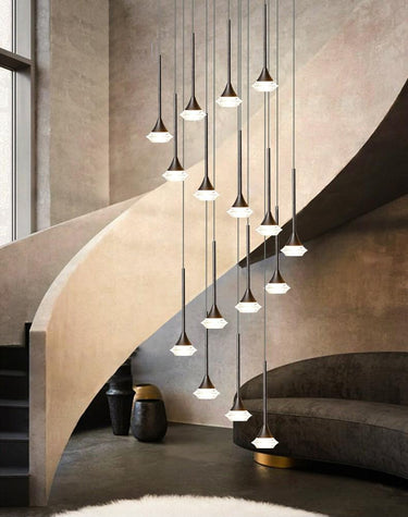 A series of pendant LED lights with a chrome metal frame and glass diffusers, installed in a spiral pattern over a staircase with a black canopy and a round lighting source.